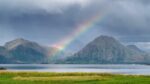 Regenbogen im Fjord vor norwegischen Bergen
